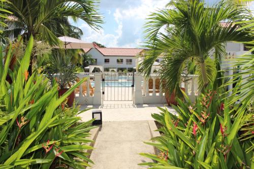 a walkway with palm trees and a white fence at VAIA HOTELES in Coveñas
