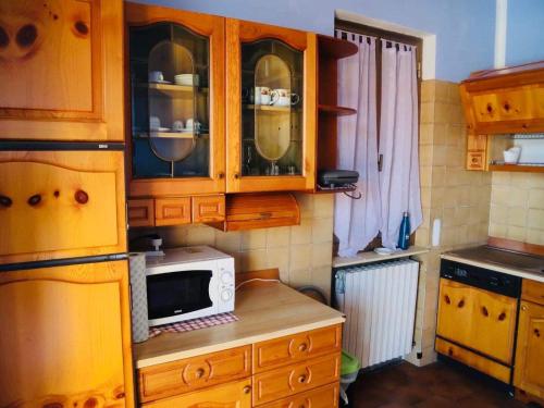 una cocina con armarios de madera y microondas en una encimera en appartamento in prè, en Borgo Ticino