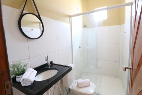 a bathroom with a sink and a toilet and a mirror at POUSADA SOLAR DOS MOREIRAS in Guajiru