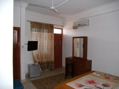 a bedroom with a bed and a dresser and a mirror at Pemicsa Hotel Accra in Spintex
