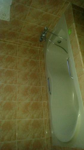 a toilet in a bathroom with a tiled floor at Pemicsa Hotel Accra in Spintex