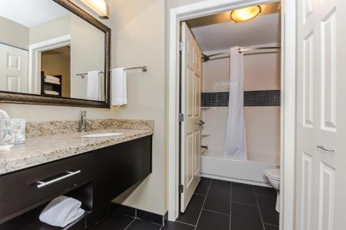 W łazience znajduje się umywalka, toaleta i lustro. w obiekcie Staybridge Suites Grand Forks, an IHG Hotel w mieście Grand Forks