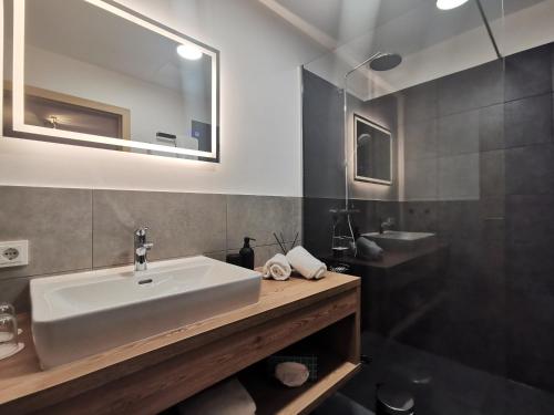 ein Bad mit einem Waschbecken, einem Spiegel und einer Dusche in der Unterkunft Sieghards Home in Mayrhofen