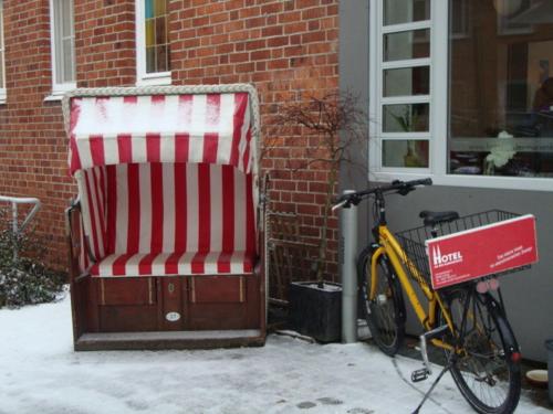 a bike parked next to a building with a red and white chair at Hotel an der Marienkirche in Lübeck