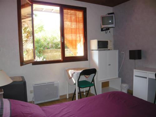 a bedroom with a bed and a table and a window at MARC in Saint-Paul-Trois-Châteaux