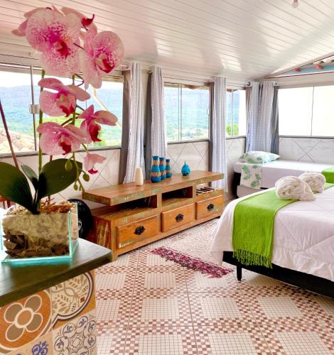 a bedroom with a bed and a large window at Pouso das Flores - Próximo a Maria Fumaça in Tiradentes