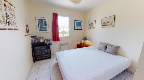 1 dormitorio con cama blanca y ventana en Villa La Grande Vallée en Saint-Gilles-Croix-de-Vie