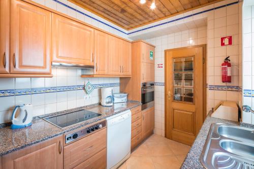 a kitchen with wooden cabinets and a sink at Private 2 Bed Apartment in Albufeira Old Town in Albufeira