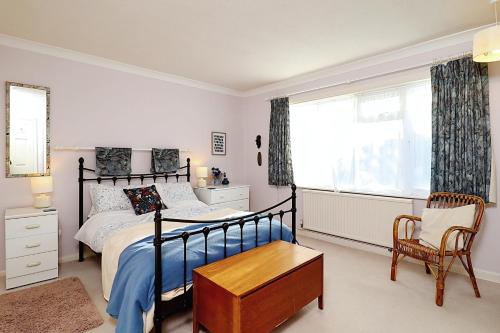a bedroom with a bed and a chair and a window at Whitestones in Brighstone