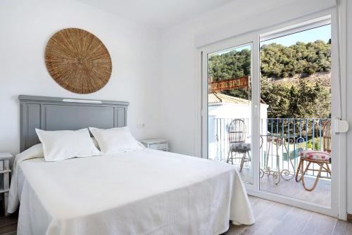 a white bedroom with a bed and a balcony at Casa de 10 Dúplex in Vejer de la Frontera