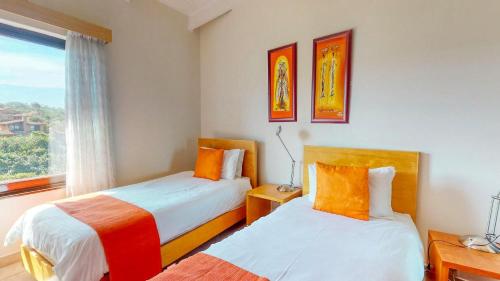 two beds in a room with a window at San Lameer 3123 by Top Destinations Rentals in Southbroom