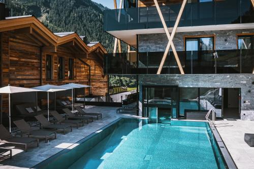 a hotel with a swimming pool in front of a building at GLEMM by AvenidA Superior Hotel & Residences in Saalbach Hinterglemm