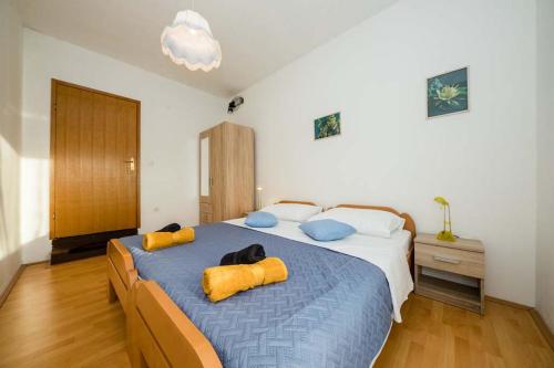 - une chambre avec un grand lit et 2 oreillers jaunes dans l'établissement Apartmani Luka, à Rab