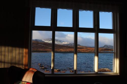 a window with a view of the water and mountains at Bygdin Høyfjellshotell in Beitostøl