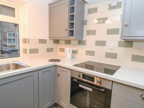 a kitchen with a stove top oven next to a sink at Firkin Cottage in Bedale