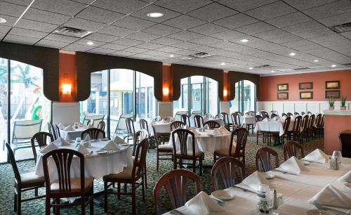 a dining room with white tables and chairs and windows at Grande Cayman Resort in Myrtle Beach