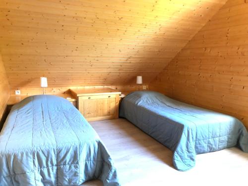 una camera con due letti in una mansarda in legno di Chalet Myrtille a Gérardmer