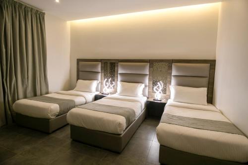 two beds in a hotel room with lights on them at Arayik Resort in Taif