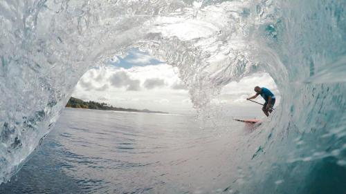 Ein Mann reitet eine Welle auf einem Surfbrett im Wasser in der Unterkunft Chris Guest House in Rincon