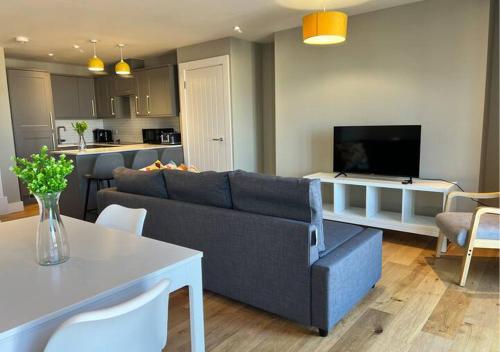 a living room with a blue couch and a kitchen at Margate Seaside Haven With 2 Terraces Sleeps 6 in Kent