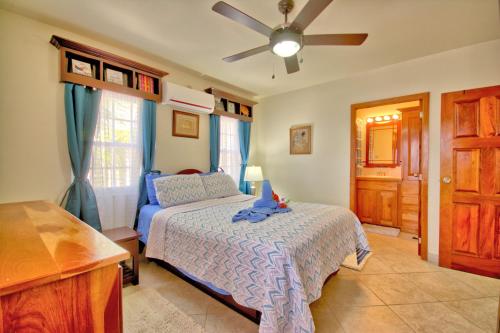 Un dormitorio con una cama y un ventilador de techo. en La Perla Azul Beach House with Pool and 4 seater cart, en San Pedro