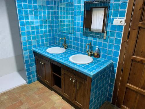 Baño de azulejos azules con 2 lavabos y espejo en Casa Rural Los Robles de Acebo II, en Acebo
