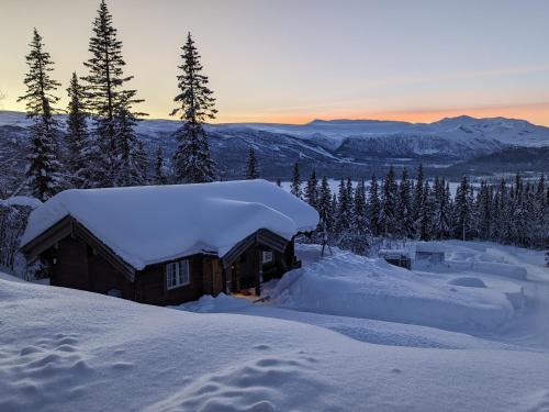 una cabaña de madera cubierta de nieve en las montañas en Liaplassen Fjellhytte en Beitostøl