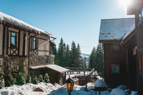a house in the snow next to a building at GORGANY resort & SPA in Yablunytsya