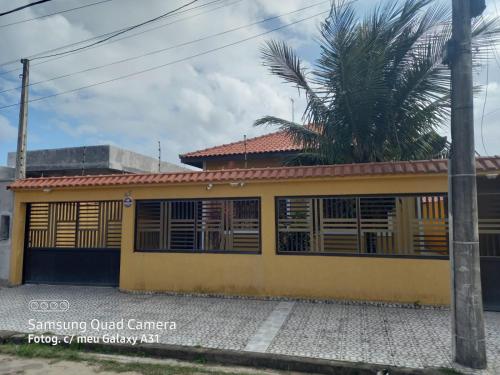 a yellow house with a palm tree in front of it at Casa pé na areia (50 mestros da praia) in Peruíbe