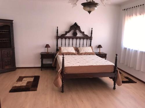 ein Schlafzimmer mit einem Bett, zwei Tischen und einem Fenster in der Unterkunft A Terraza da Filipa in Vila Praia de Âncora