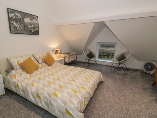 a bedroom with a bed and chairs in a attic at Bronwen House in Llanbedr