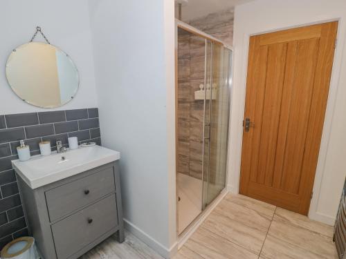 uma casa de banho com um chuveiro, um lavatório e um espelho. em Bronwen House em Llanbedr