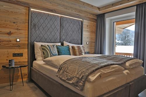 um quarto com uma cama grande e uma janela grande em Sieglhub Chalets - Appartements - Hotel em Flachau