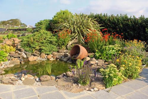 a garden with a pond with rocks and plants at Carnalbanagh House in Portstewart