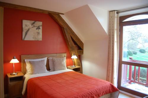 1 dormitorio con pared roja, cama y ventana en Gîte dans un Domaine Historique, en Chevreuse