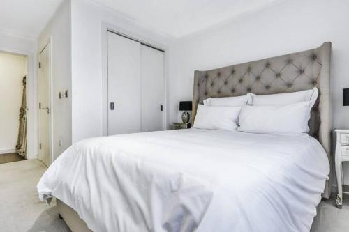 a white bedroom with a large bed with white sheets and pillows at Tower Bridge Lux-Penthouse in London