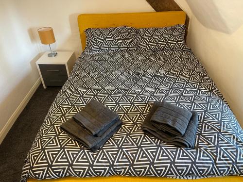 a bed with black and white sheets and pillows at Blackbird Cottage in Kettering