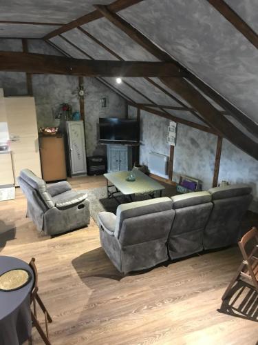 ein Wohnzimmer mit Sofas und einem Tisch in der Unterkunft La Grange Aux Fleurs in Rigny-la-Nonneuse