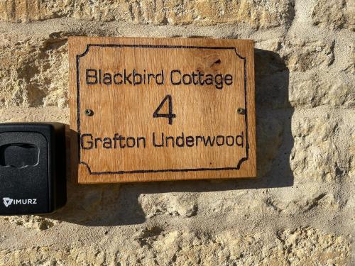 a wooden sign on a stone wall at Blackbird Cottage in Kettering