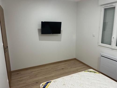 Dieses weiße Zimmer verfügt über einen Flachbild-TV an der Wand. in der Unterkunft Charmant pavillon de 70 m2 in La Charité-sur-Loire