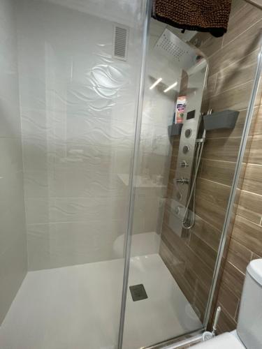 a shower with a glass door next to a toilet at San Blas Apartment - Alicante City in Alicante