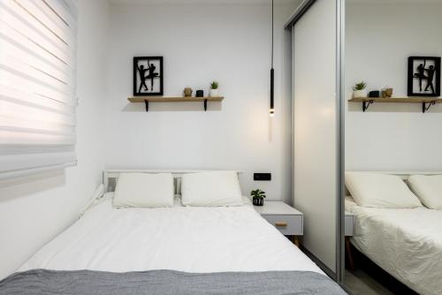 a white bedroom with a bed and a mirror at Luxury Central Old Town Apartment in Beer Sheva