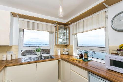 a kitchen with a sink and two windows at 8 Dolphin Court in Brixham