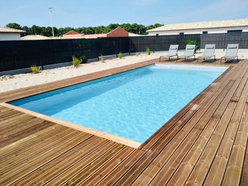 - une piscine avec une terrasse en bois et des chaises dans l'établissement L'Océane Villa 8 pers. PISCINE CLIM WIFI océan, à Vensac
