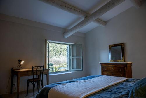 een slaapkamer met een bed, een bureau en een raam bij Maison au pied des collines du Luberon à Lourmarin hameau des Lointes Bastides in Lourmarin