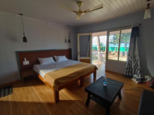 a bedroom with a bed and a table in it at Coral Beach Cottage in Māvalli