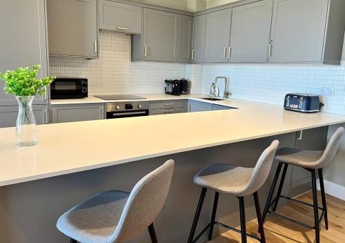 a kitchen with a counter with two stools at Margate Beach Front Apt With Sea Views Sleeps 6 in Kent