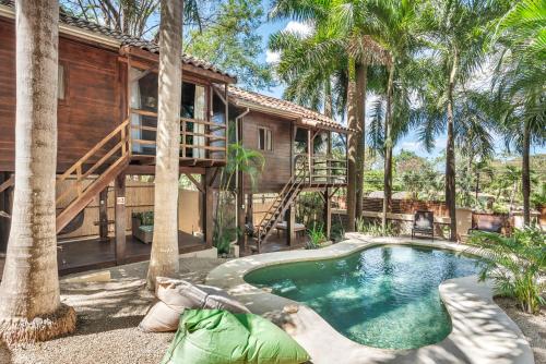 a house with a swimming pool and palm trees at The Beach Bungalows - Yoga and Surf House - Adults Only in Tamarindo