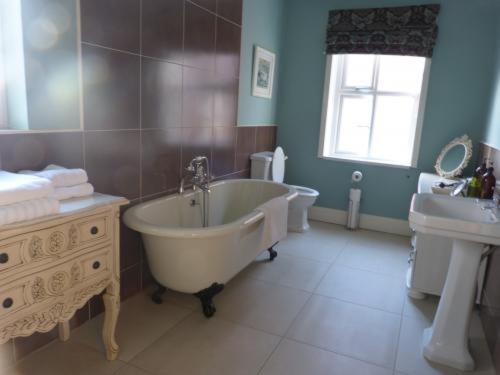 a bathroom with a bath tub and a sink at Inglewood in Chorley