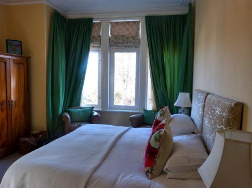 a bedroom with a large bed with green curtains at Inglewood in Chorley